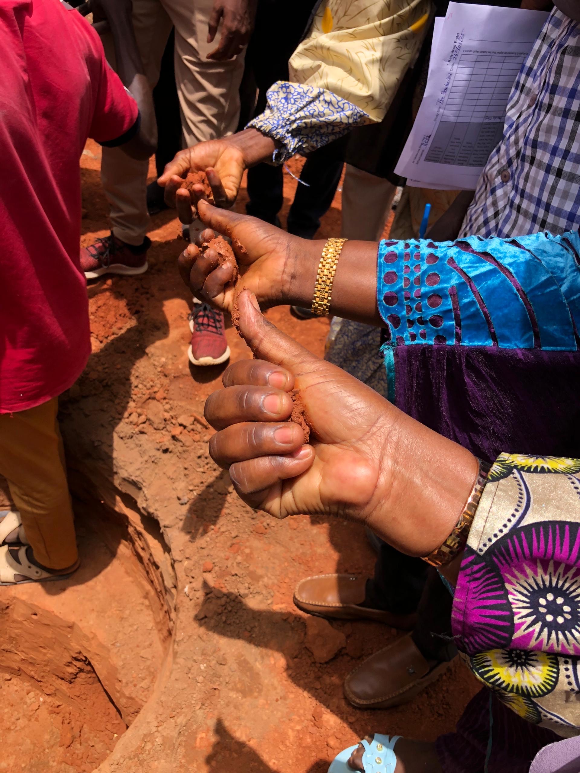 Group holding red soil in their hands.